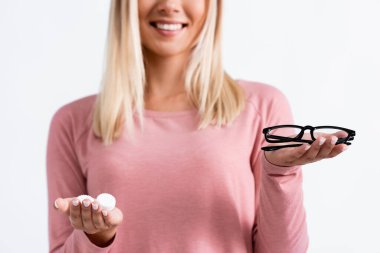Cropped view of eyeglasses and contact lenses in hands of smiling woman on blurred background isolated on white clipart
