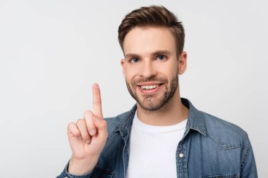 Gri renkli lensleri tutarken gülümseyen adam kameraya bakıyor.