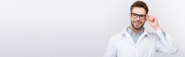 Gülümseyen doktor gözlüklere dokunurken gri pankartta izole bir şekilde yüzünü çeviriyor. 
