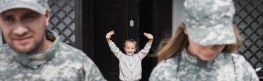 Happy girl with waving hands standing near house door with blurred man and woman in military uniforms on foreground, banner clipart