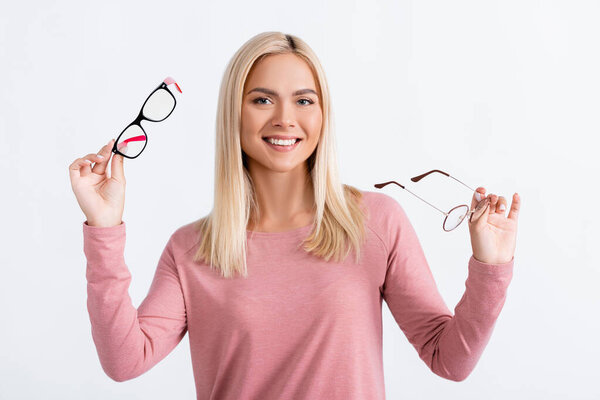 Positive woman looking at camera while holding eyeglasses isolated on grey