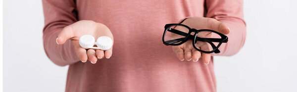 Cropped view of young woman holding box with contacts and eyeglasses isolated on grey, banner 