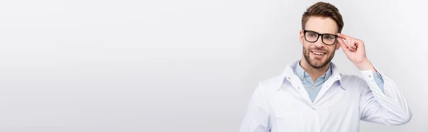 Усміхнений Лікар Торкається Окулярів Дивлячись Ізольовано Сірому Банер — стокове фото