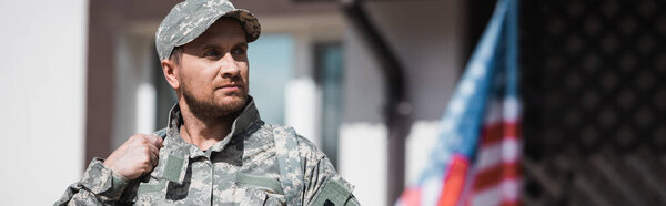 Военный, смотрящий в сторону с размытым американским флагом на заднем плане, баннер