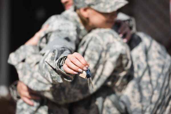 Keys with blurred military wife and husband embracing on background