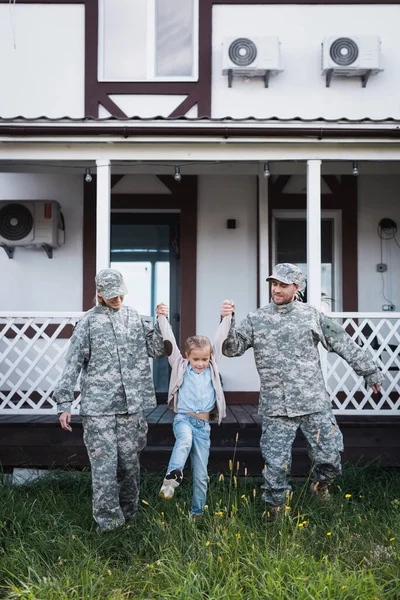 Sonriente Padre Militar Madre Levantando Hija Sobre Hierba Patio Trasero — Foto de Stock