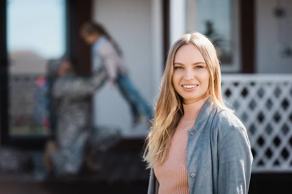 Happy Adult Woman Looking Camera While Standing Backyard Blurred Military — Stock Photo, Image