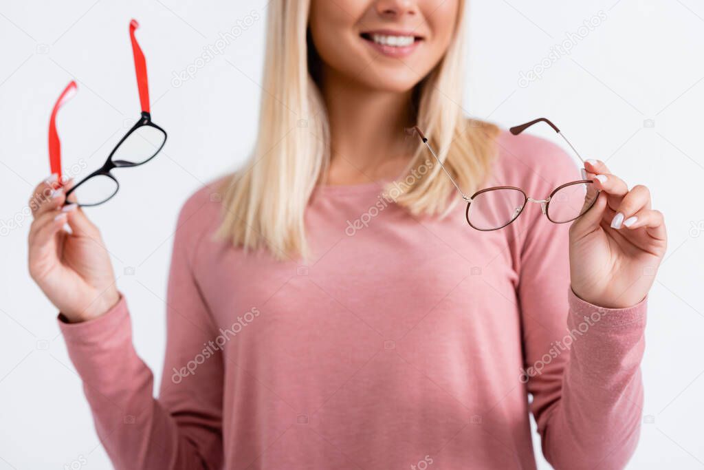 Cropped view of smiling woman holding eyeglasses on blurred background isolated on grey