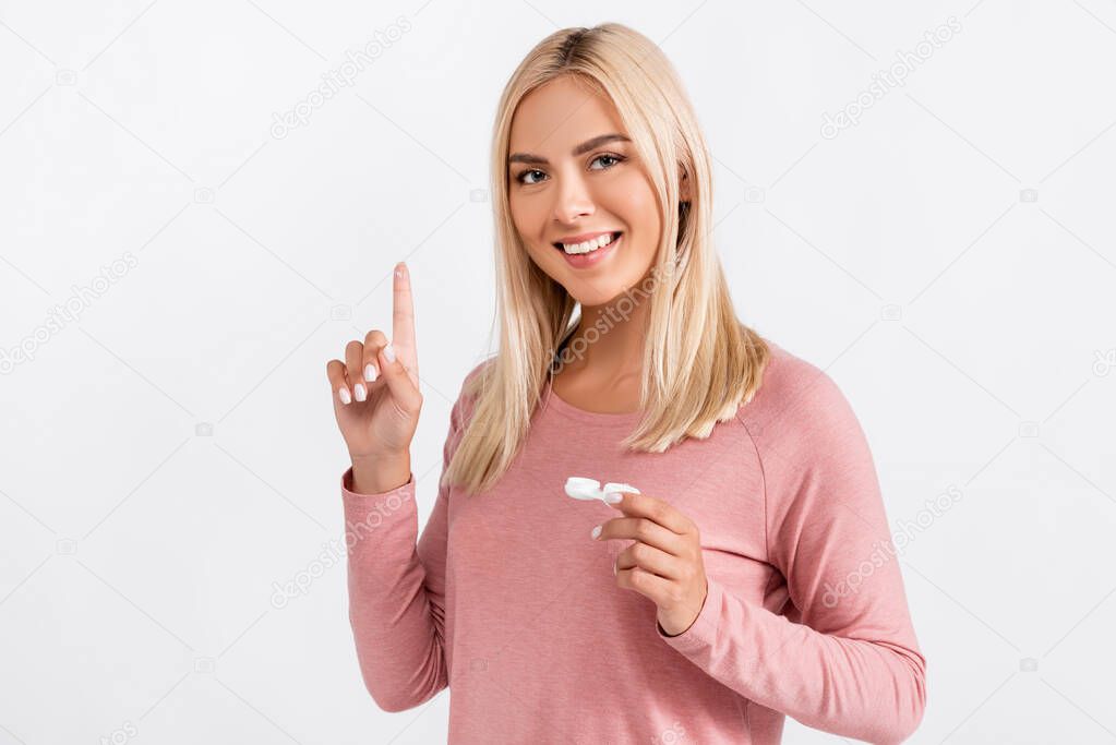 Blonde woman holding contact lens and container isolated on grey