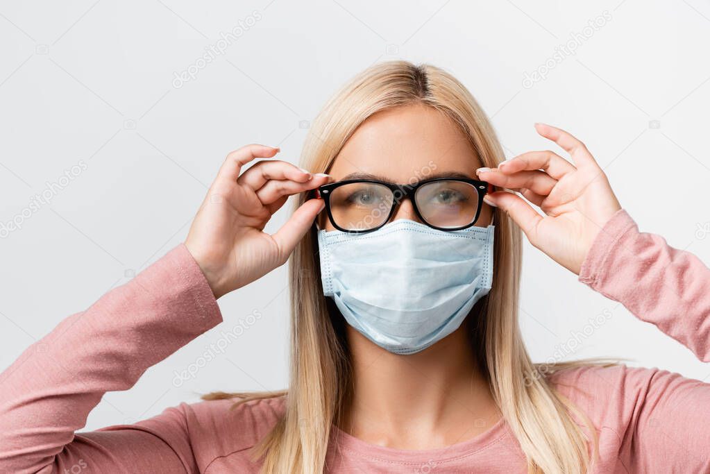 Young woman in medical mask holding misted eyeglasses isolated on grey