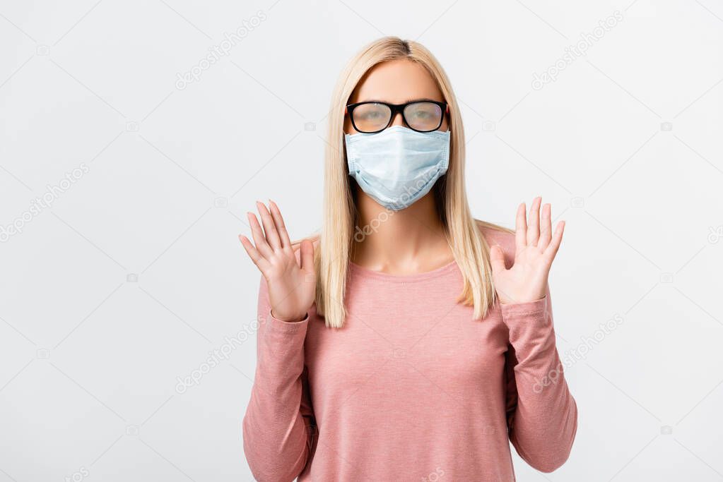 Young woman in misted eyeglasses and medical mask standing isolated on grey
