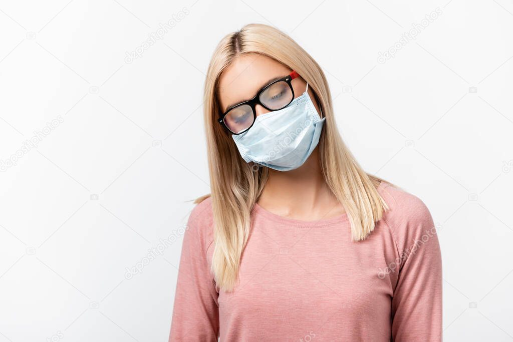 Young woman in medical mask looking at misted eyeglasses isolated on grey
