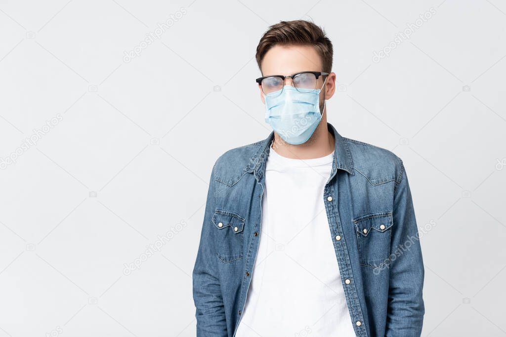 Man in medical mask and misted eyeglasses isolated on grey
