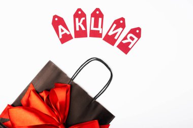 Beyaz arka planda fiyonklu alışveriş çantasına Kiril alfabesiyle yazılmış fiyat etiketlerinin üst görünümü