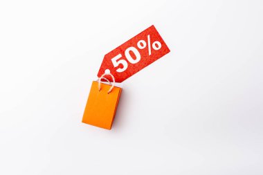 Top view of price tag with 50 percent signs and toy shopping bag on white background clipart