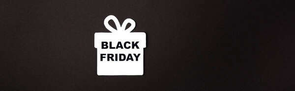 Panoramic shot of paper gift box with black friday lettering on black background 