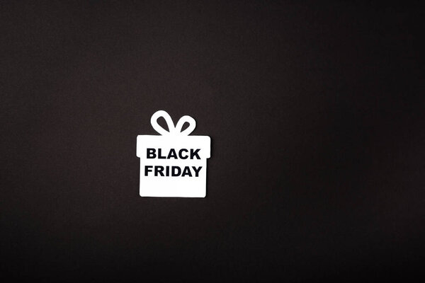 Top view of paper gift box with black friday lettering on black background 