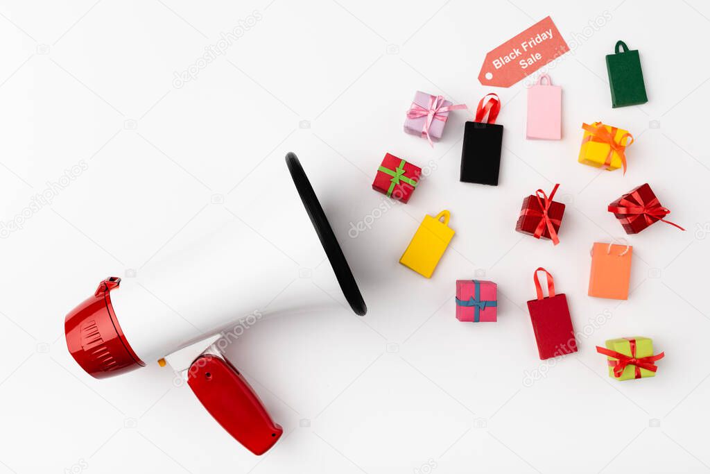 Top view of loudspeaker and small shopping bags, gifts and price tag with black friday sale lettering on white background