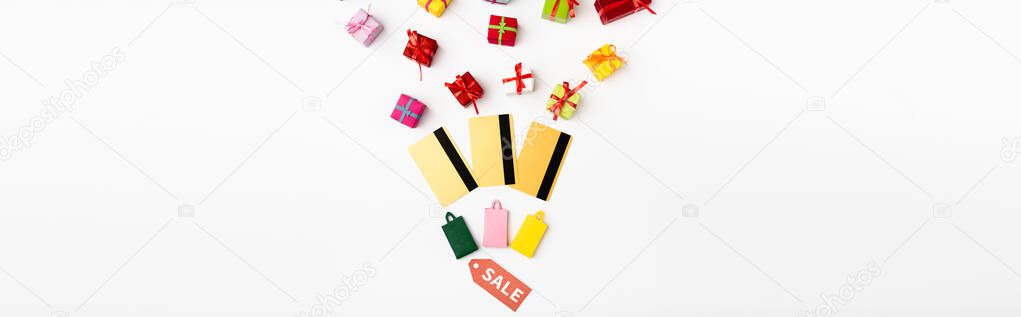 Panoramic orientation of price tag with sale lettering near credit cards and toy gifts on white background