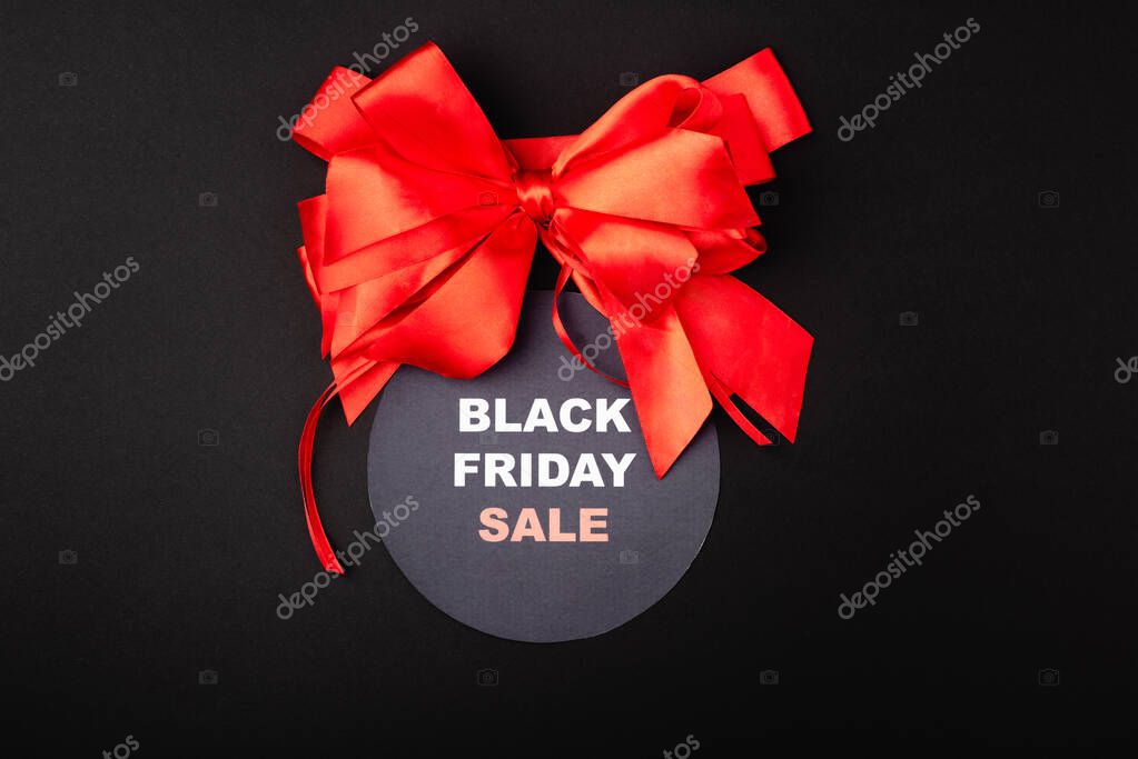 Top view of red bow with black friday sale on circle on black background