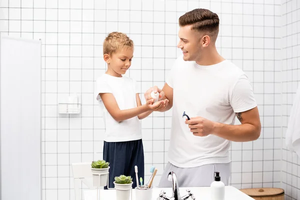 Güler Yüzlü Baba Banyoda Tıraş Köpüğü Sıkan Jiletle Oğlunun Ellerinde — Stok fotoğraf
