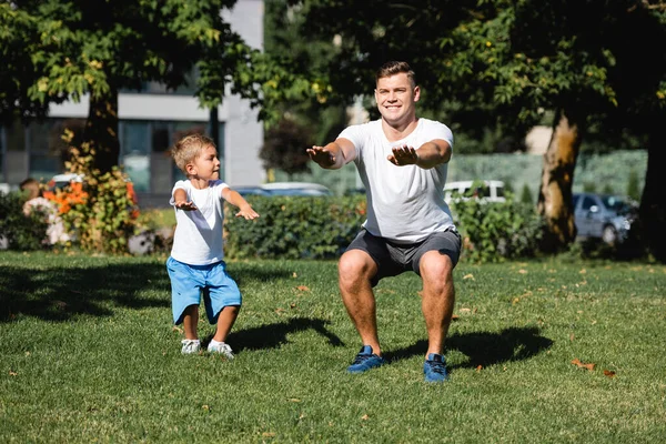 Niño Con Las Manos Extendidas Con Ropa Deportiva Cuclillas Mirando — Foto de Stock