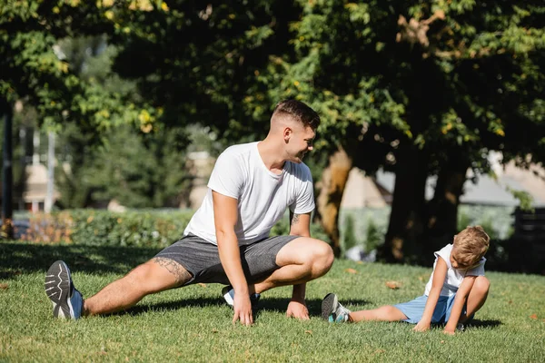 Sonriente Joven Adulto Haciendo Embestidas Mientras Mira Chico Ropa Deportiva — Foto de Stock