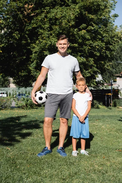 笑顔男でスポーツウェアとともにボール包含する未就学児の男の子とともにクリーンな手で公園 — ストック写真