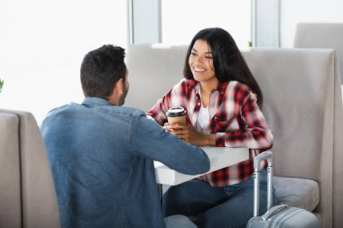 Mutlu Afro-Amerikan kadını, bulanık ön planda tek kullanımlık bardağı erkeğin yanında tutuyor. 