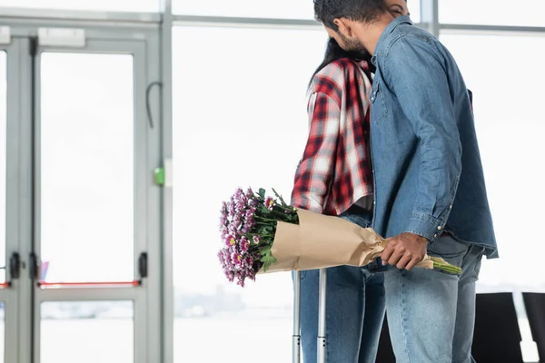 Hombre Sosteniendo Flores Envueltas Mientras Encuentra Con Novia Afroamericana Aeropuerto — Foto de Stock