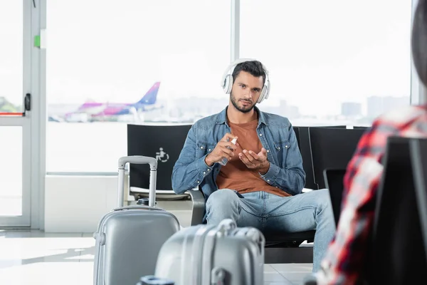 Uomo Barbuto Cuffia Utilizzando Disinfettante Aeroporto Vicino Passeggero Primo Piano — Foto Stock