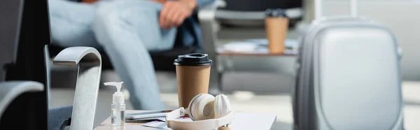 無線ヘッドフォン サニタイザー付きボトル 空港の使い捨てカップがぼやけている背景 — ストック写真