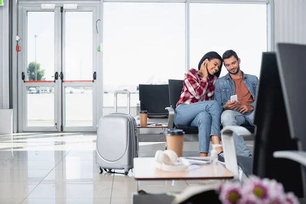 Happy Interracial Couple Looking Phone Departure Lounge Airport Blurred Foreground — Stock Photo, Image