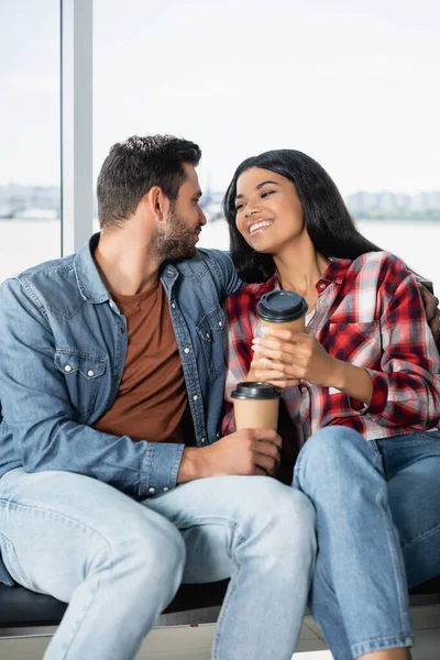 Happy Multicultural Couple Holding Coffee While Sitting Departure Lounge Airport — Stock Photo, Image