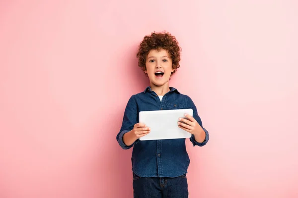 Vzrušený Kudrnatý Chlapec Otevřenými Ústy Drží Digitální Tablet Růžové — Stock fotografie