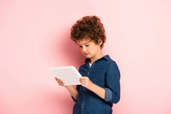 Lockig Pojke Jeansskjorta Tittar Digital Tablett Rosa — Stockfoto