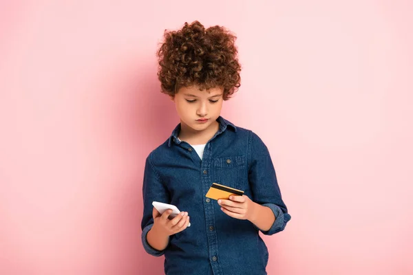 Krullende Jongen Met Smartphone Creditcard Tijdens Het Online Winkelen Roze — Stockfoto