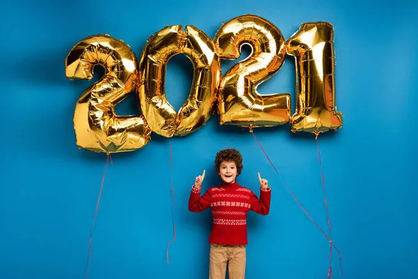 Excited Boy Red Sweater Pointing Fingers Golden Balloons 2021 Numbers — Stock Photo, Image