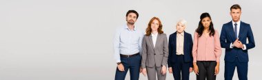 Pensive businesspeople looking at camera while standing isolated on grey, banner 