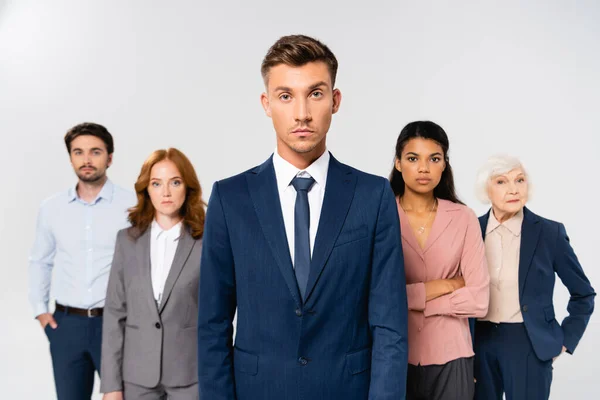 Businessman Suit Looking Camera Multicultural Colleagues Blurred Background Isolated Grey — Stock Photo, Image