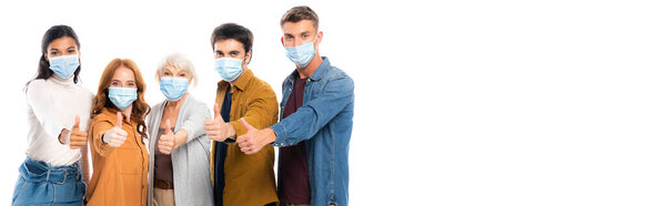 Multicultural friends in medical masks showing thumbs up gesture isolated on white, banner 