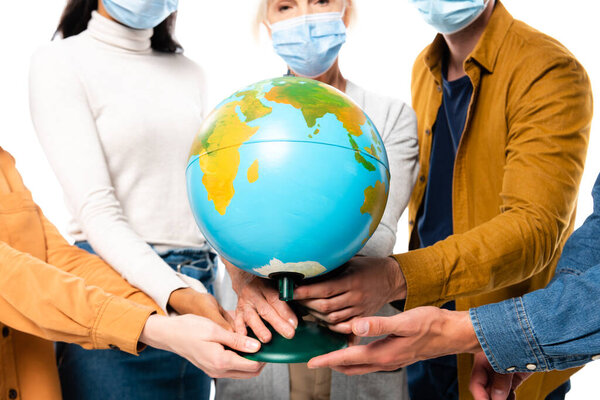 Cropped view of multiethnic people in medical masks holding globe isolated on white