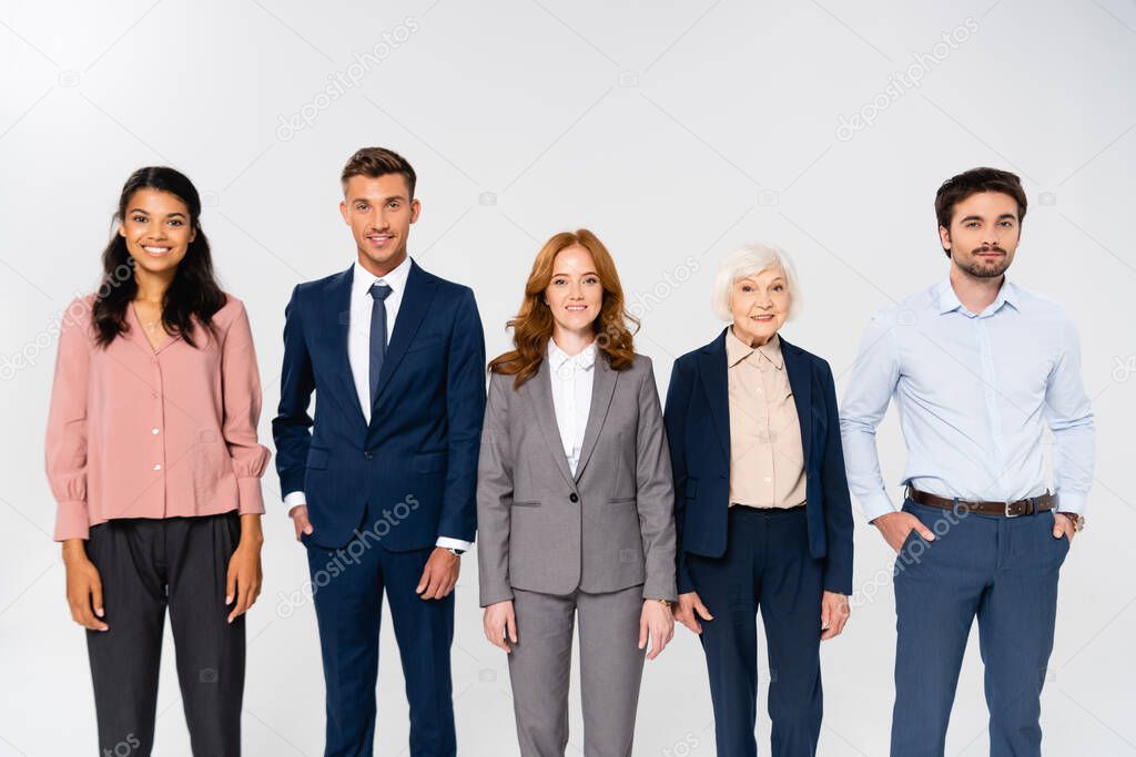 Cheerful multiethnic businesspeople looking at camera isolated on grey