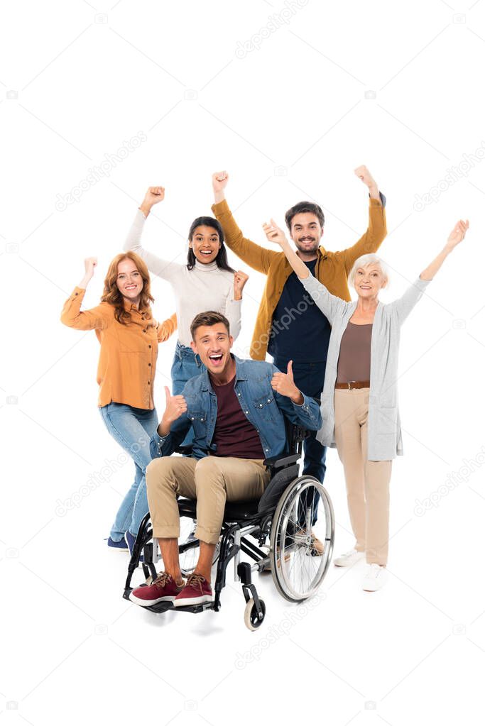 Excited multiethnic friends showing like and yeah gestures near friend in wheelchair on white background