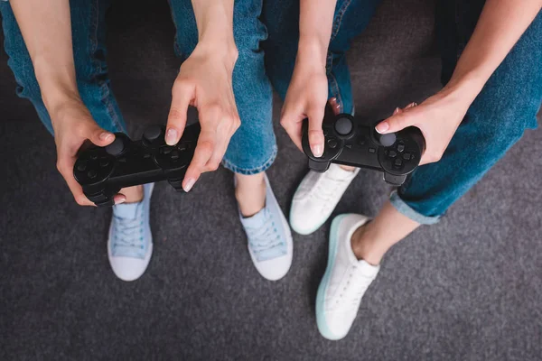 Tiro cortado de dois amigos do sexo feminino jogando videogame com joysticks em mãos — Fotografia de Stock