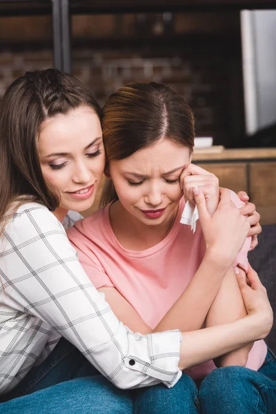 Joven mujer animando hasta llorando amigo femenino - foto de stock