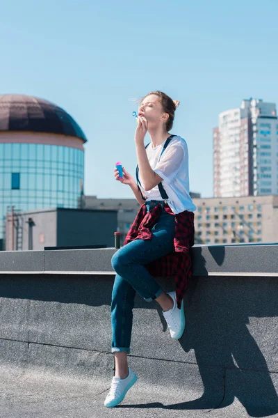 Молодая женщина использует пузырьковый воздуходув на крыше — стоковое фото