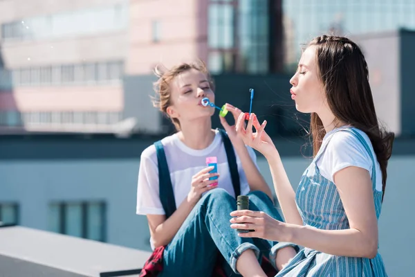 Young attractive female friends using bubble blowers at rooftop — Stock Photo