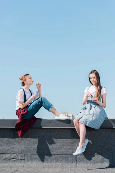 Attractive young female friends using bubble blowers at rooftop — Stock Photo