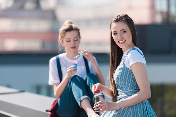 Young attractive female friends using bubble blowers at rooftop — Stock Photo